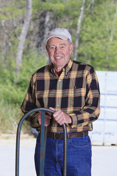 Senior man standing in a warehouse with a hand truck