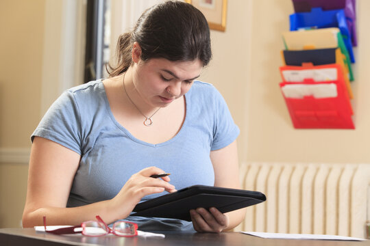 Woman with Asperger syndrome using her tablet to do work in home office