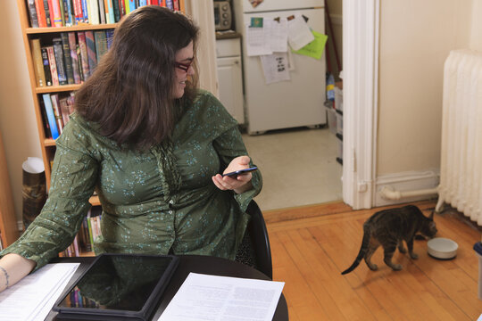 Woman with Asperger syndrome working in her home office and watching her cat