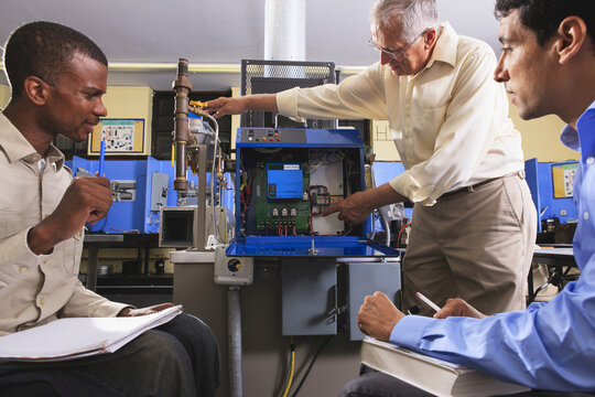 Professor demonstrating furnace electronic control system in HVAC classroom with students