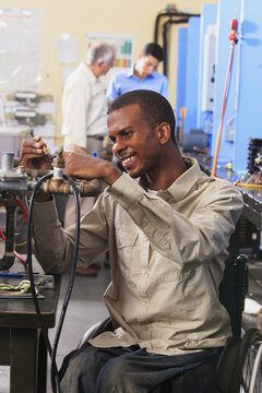 Student in wheelchair examining furnace ignitor in HVAC classroom