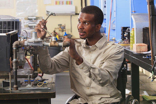 Student in wheelchair examining furnace ignitor in HVAC classroom