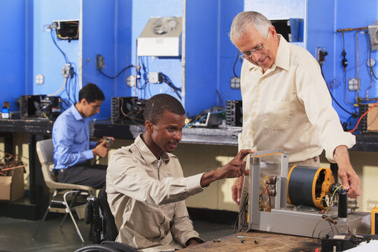 Student in wheelchair setting up generator experiment with professor while student examines HVAC system