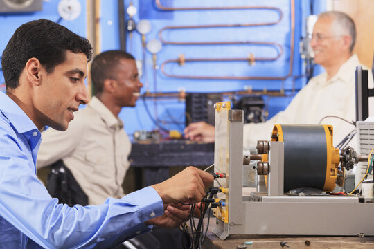 Student setting up generator experiment while instructor discusses HVAC system to student in wheelchair