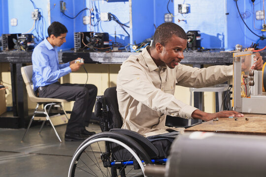 Student in wheelchair setting up generator experiment while student examines HVAC system