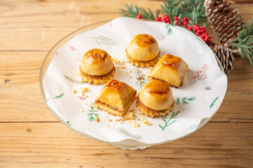 Top view of cream cakes with biscuit on plate and wooden table with Christmas decorations, horizontal, with copy space