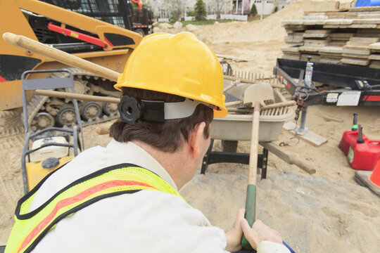 Construction supervisor with Spinal Cord Injury putting shovel into wheelbarrow