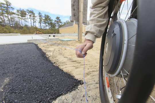 Construction supervisor with Spinal Cord Injury pulling chalk line at edge of pavement
