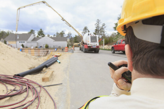 Construction supervisor with Spinal Cord Injury on walkie talkie to concrete pump pouring foundation