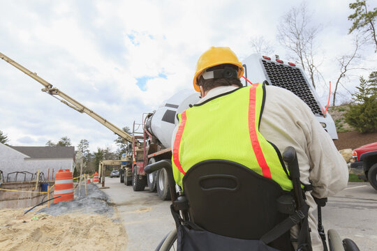 Construction supervisor with Spinal Cord Injury on walkie talkie to concrete pump pouring foundation