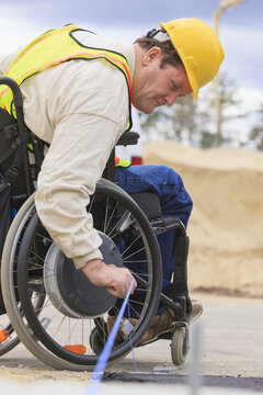 Construction supervisor with Spinal Cord Injury pulling chalkline at edge of pavement