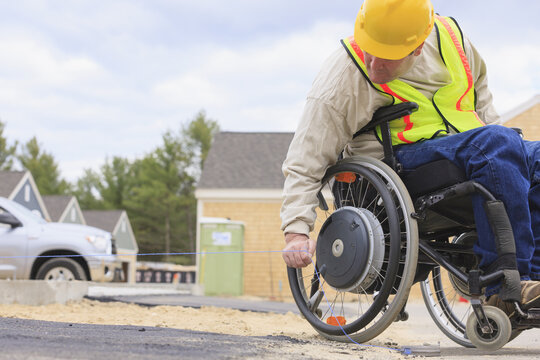Construction supervisor with Spinal Cord Injury pulling chalkline at edge of pavement