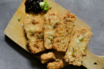 Fried tempeh on a cutting board with sweet chili sauce