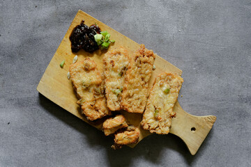 Fried tempeh on a cutting board with sweet chili sauce