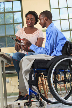 Engineering students making measurement on microcontroller board in an electronics classroom, one in a wheelchair