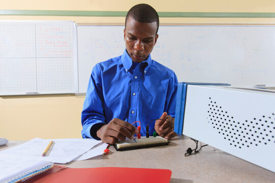 Engineering student in an electronics classroom in a wheelchair from Spinal Meningitis preparing a prototyping breadboard