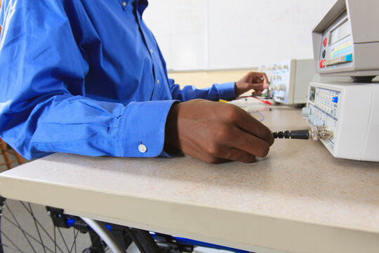 Engineering student in an electronics classroom in a wheelchair from Spinal Meningitis preparing a prototyping breadboard