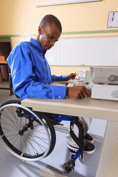 Engineering student in an electronics classroom in a wheelchair from Spinal Meningitis preparing a prototyping breadboard