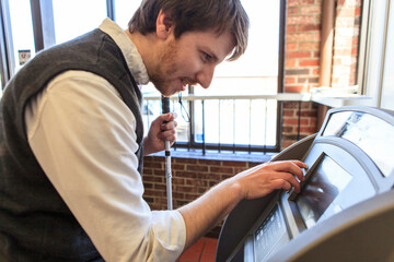 Young blind man with cane using a bank ATM