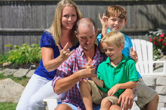 Portrait of a happy family with hearing impairments signing "I love you" in American sign language