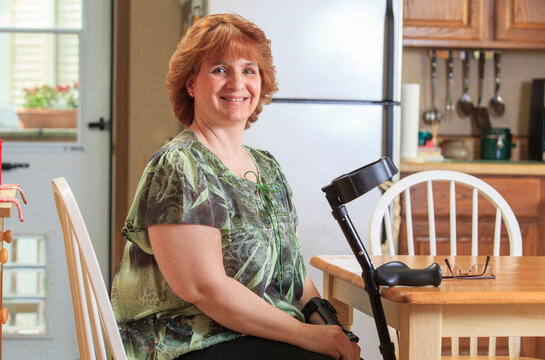 Woman with RSD using her hand brace and crutch at home