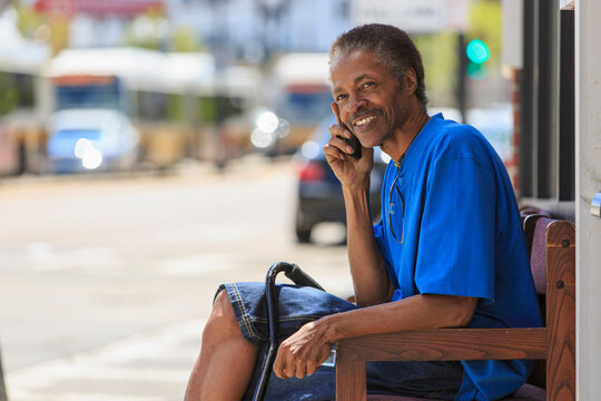 Man with Traumatic Brain Injury waiting at the bus terminal while on his phone
