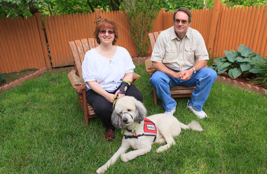 Woman with RSD and her service dog with husband sitting in their back yard