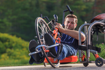 Man with spinal cord injury adjusting his feet on his custom adaptive hand cycle