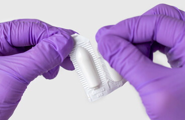 doctor hand in surgical gloves holding detach one anal or vaginal rectal suppositories anti fever...