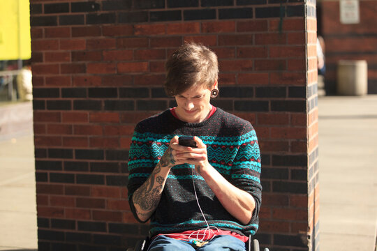 Trendy man with a spinal cord injury in wheelchair taking his text messages