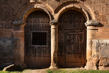 Puertas de madera antigua en un edificio de estilo románico.