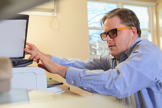 Man with congenital blindness scanning paperwork at his computer
