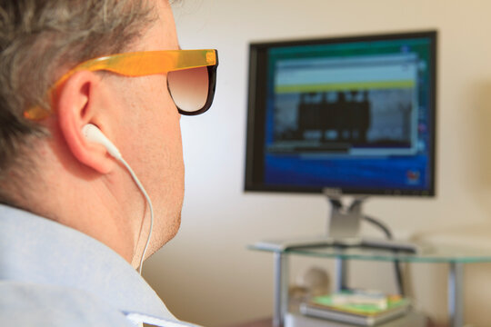 Man With Congenital Blindness Using Assistive Technology At His Computer To Listen