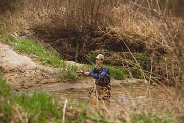 young man casting fishing pole in creek water