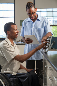 Two students who had Spinal Meningitis collecting data on tablet from oscilloscope in laboratory