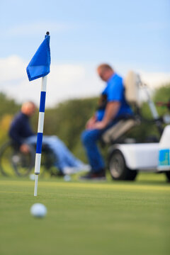 Two men with spinal cord injuries waiting at golf putting green