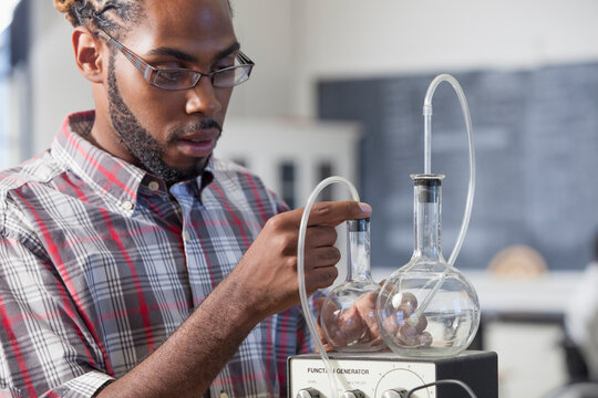Student who had Spinal Meningitis setting up flasks for a volume versus pressure experiment in laboratory