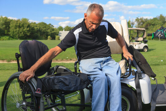 Man with spinal cord injury in an adaptive golf cart getting into his wheelchair