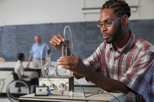 Student who had Spinal Meningitis and has hearing impairment setting up flasks for a volume versus pressure experiment in laboratory