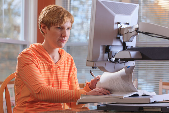 Young woman with visual impairment working at her desktop magnifier