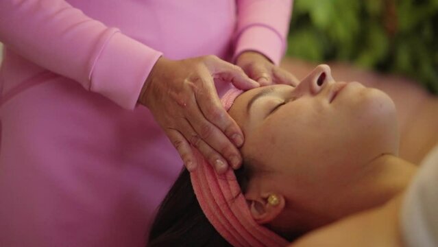 Close-up shot of a woman enjoying facial treatment with clay mask at beauty shop. Cosmetology and spa
