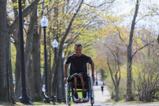 Man in a wheelchair who had Spinal Meningitis going through a park