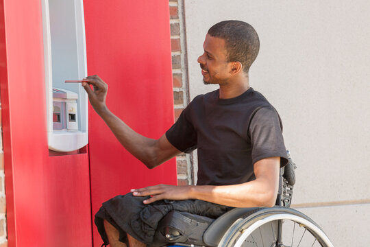 Man in a wheelchair who had Spinal Meningitis using a bank ATM