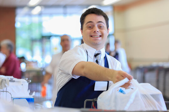 Man with Down Syndrome holding a bag while working at a grocery store