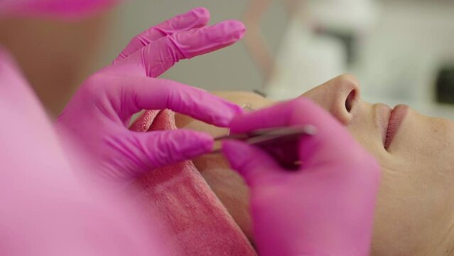 make-up artist combing and styling eyebrows after the procedure of correction and coloring of eyebrows
