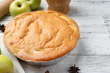 apple pie charlotte on white wooden table with fresh apple and cinnamon