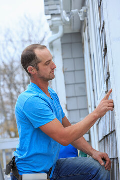 Home repairman with a hearing aid checking the damage on the house