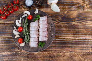 Raw chicken skewer with bacon on a wooden board. Top view. Copy space for text or logos