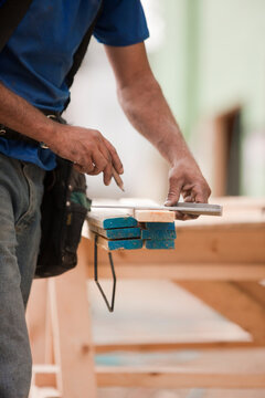 Hispanic carpenter measuring boards with a rafter square at a house under construction