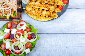 Traditional Greek cuisine concept. Greek food served with Greek salad, chicken souvlaki and gyro pita, top view.  Copy space for text or logo.